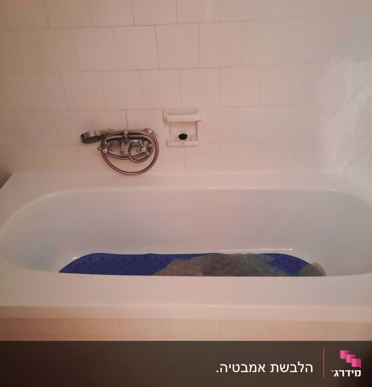 אמבטיה לבנה עם ברז מתכת וקיר אריחים לבנים